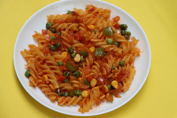 Red fusillli pasta with vegetables, corn, peas, red sauce