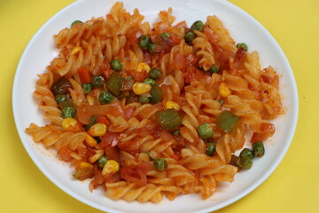 Red fusillli pasta with vegetables, corn, peas, red sauce