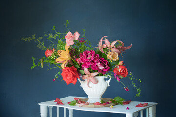 bouquet of summer flowers in vase on vintage white wooden shelf on dark background