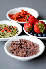 Various legumes and different kinds of nuts in spoons. Walnuts kernels ,hazelnuts, almond ,brown pinto ,soy beans ,flax seeds ,chia ,red kidney beans and pecan set up on white gray background
