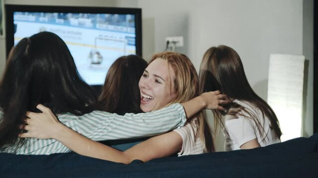 Excited millenials cheering for team sitting in living room. Backshot group of teens watching hockey match on tv celebrating goal. Concept of leisure, lifestyle, spending time together, victory.