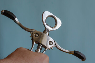 Adult man holds a metal corkscrew in his hand.