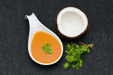 Coconut chutney with fresh raw coconut cut in half with coriander leaf.  best served with Idli, Idly Dosa Vada in Kerala Tamil Nadu South India. Top view of Indian food.