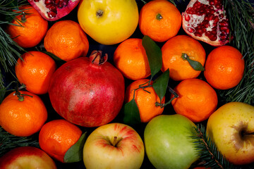 Background of mandarin, apples, pomegranates and pine branches