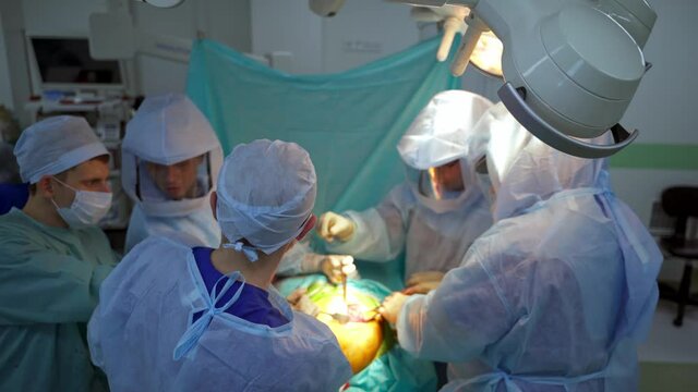 Operating theater in hospital. Teamwork of male surgeons during the operation on a patient in the operating room.