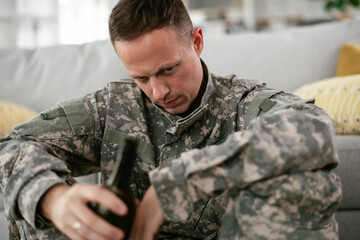 Fototapeta premium Depressed soldier with bottle sitting in livig room., Alcohol addiction. 