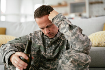 Depressed soldier with bottle sitting in livig room., Alcohol addiction.	