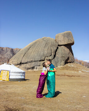 Couple kissing in sleeping bags in front of Turtle rock and ger in Gorkhi Terelj national park, Mongolia