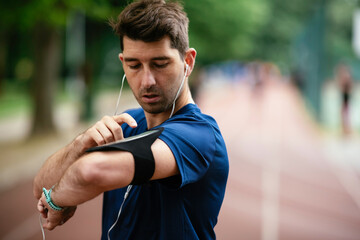 Young man checking his heart rate during work out. Young man exercising on the athletics track	