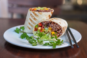 Vegan burrito. Sliced up raw food wrap with vegan ingredients on a plate