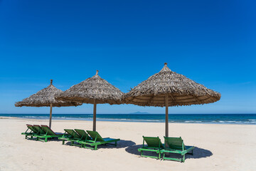 Tropical sand beach and summer sea water with blue sky and straw umbrella. Travel and nature concept