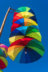 Street lamps decorated with colorful umbrellas hang on a pillar in street against the blue sky on a sunny day