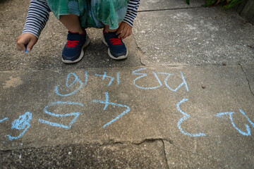 Small kid writing numbers with chalk.