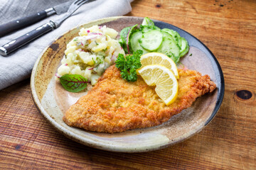 Traditioneles frittiertes Wiener Schnitzel vom Kalb mit Kartoffel und Gurkensalat angeboten als...