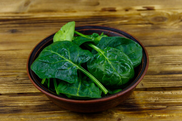 Fresh green spinach leaves in bowl on a wooden table