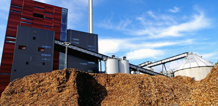 bio power plant with storage of wooden fuel against blue sky