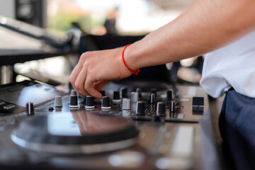 DJ playing music at outdoor event. Person operating mixer at music festival. Close up shot of deejay mixing at the party