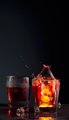 Pieces of ice fall into a frosted glass with whiskey.