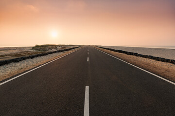 Fototapeta premium he black road heading straight ahead. Flanked by the sea at Dhanushkodi, Tamil Nadu, India.