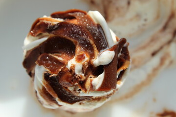 Melted and decorated white Ice Cream with chocolate flavour on top of it. close and cropped display.