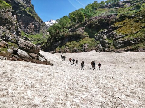 Manali, India - June 12th 2019: Bunch of people in a trekking group climbing on a slippery glacial valley to reach Indian Himalayan Mountain Top.