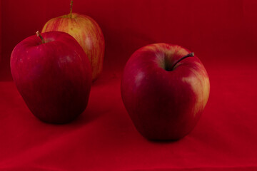 three delicious shiny apple on a red studio background