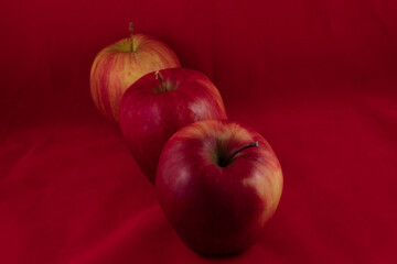 three delicious shiny apple on a red studio background