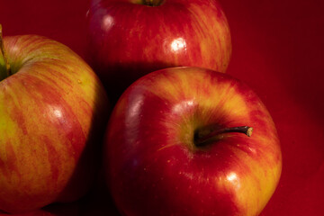close up of many delicious shiny apple on a red studio background