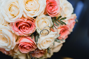 Wedding rings of the bride and groom on the background of a bouquet
