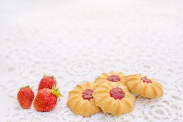 cookies with jam and strawberries lying on a white openwork tablecloth
