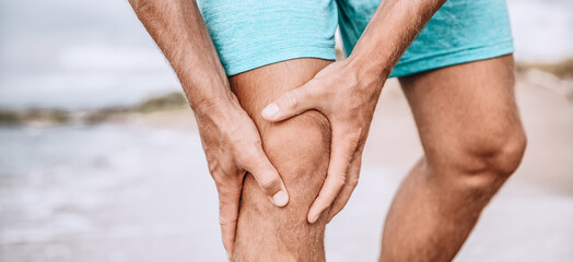 Knee pain sport injury from running exercise. Man runner holding painful knees, hurting from sprain joint or arthritis. Closeup of leg panoramic. Jogging sport.
