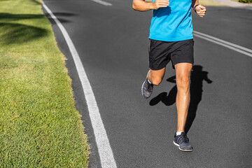 Fototapeta premium Runner man training marathon run jogging in running shoes on city road street outdoor sprinting fast. Closeup of shoes and legs.