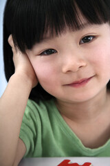 Obraz premium Girl smiling and resting head in hand