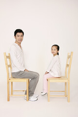 Obraz premium Man and girl sitting on wooden chairs