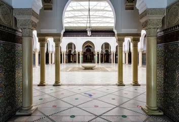 Deurstickers The peristyle of the Great Mosque of Paris, France, borders a tiled courtyard with a circular ablutions basin in the center, covered by a retractable soft roof. © olrat