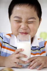 Boy closing his eyes before drinking glass of milk