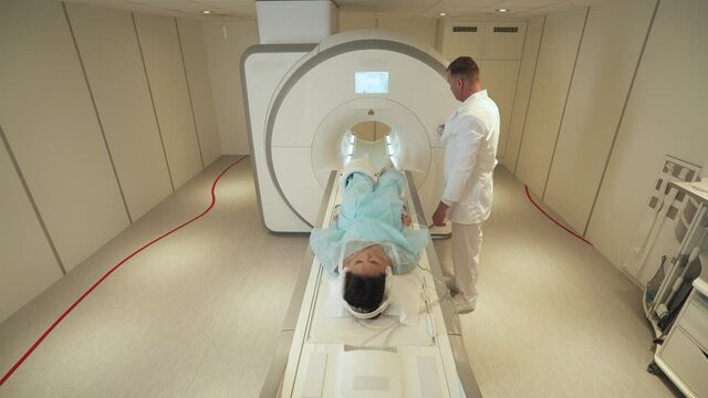 Magnetic resonance imaging, adult man doctor performs a magnetic tomographic examination of a young asian woman, MRI, modern technologies in medicine.