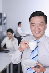 Businessman enjoying coffee with other business people are working in the background