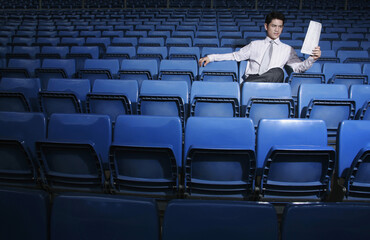 Obraz premium Businessman reading a newspaper in an empty stadium