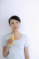 Woman contemplating while holding a glass of orange juice