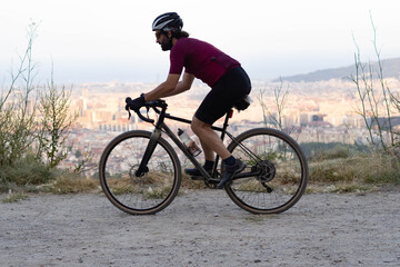Obraz premium Male cyclist with gravel bike at full speed with the city of Barcelona on the horizon