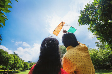 Back side faceless shot of two people flying Indian flag kite to celebrate national holiday: ...