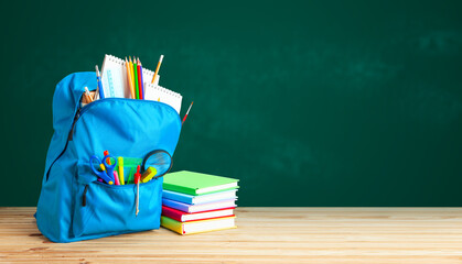 School bag. Backpack with supplies for school on the background of green blackboard. Copy space for...