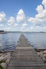 Obraz premium old bridge going out into the water with blue sky and clouds 