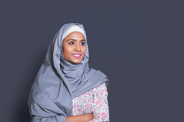 Beautiful muslim Indian young woman wearing hijab standing over grey studio background with arms crossed