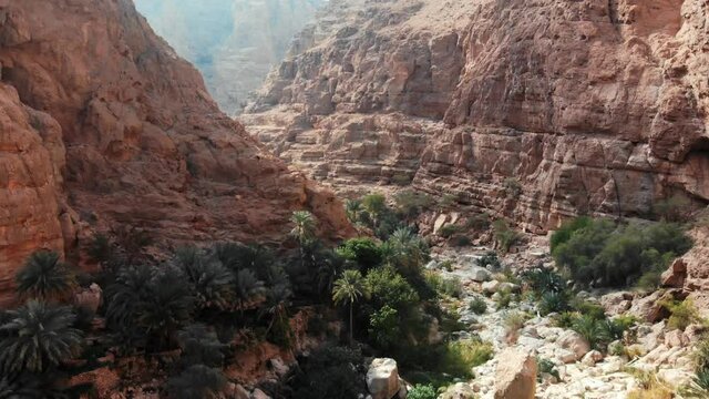 Breathtaking view of Wadi Shab with its oasis landscape scattered with palms, and stone mountains, near Tiwi, beautiful place in Oman 