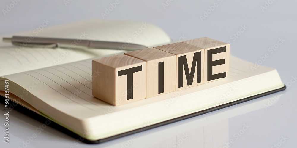 Poster time sign on a wooden block on notebook background