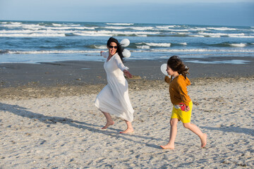 Fototapeta na wymiar Happy mom and son running on the beach