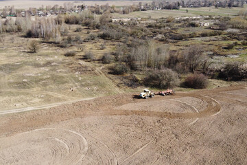 Fototapeta na wymiar Agricultural machinery in a field near a small grove, aerial view. Agricultural land.