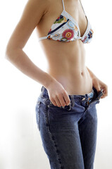 Shoulder down shot of a woman in bra wearing her jeans